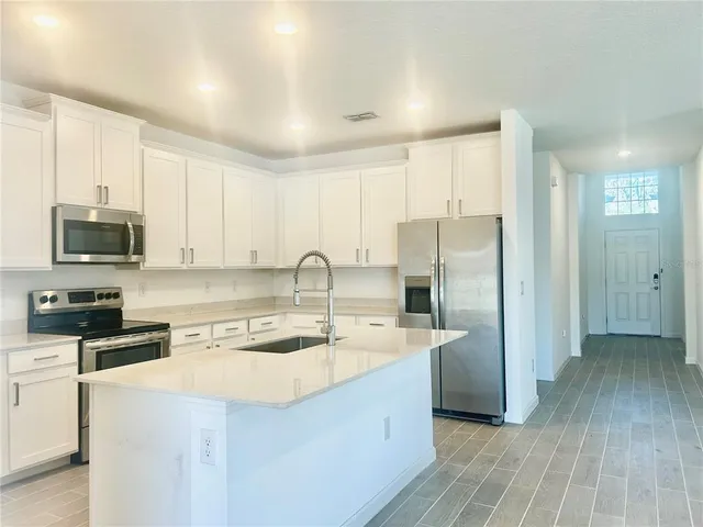 a kitchen with stainless steel appliances granite countertop a sink a stove a refrigerator and cabinets