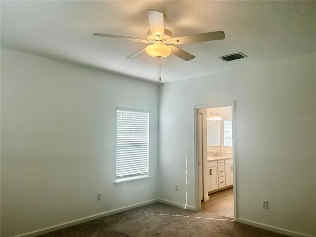 an empty room with a window and a ceiling fan