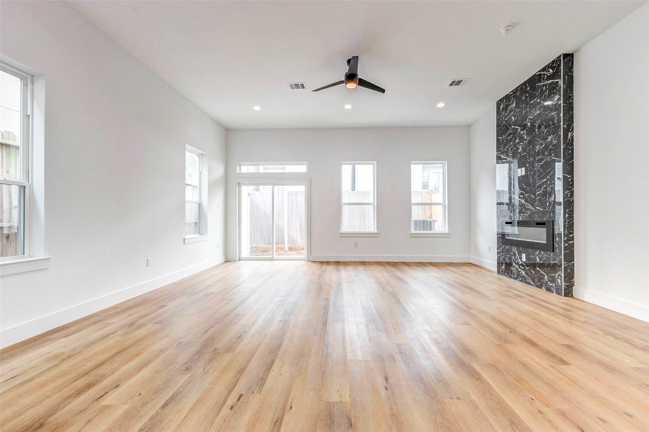 2118 Live Oak Street, Unit B Houston, TX 77003 - Photo 13 of 50 A spacious living area with tall ceilings, warm wood floors, and plenty of natural light. The sleek fireplace adds a modern focal point, giving the room a clean and comfortable feel.