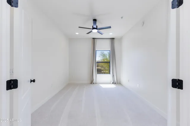 an empty room with a window and a ceiling fan