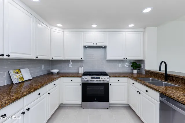 a kitchen with granite countertop white cabinets and white appliances