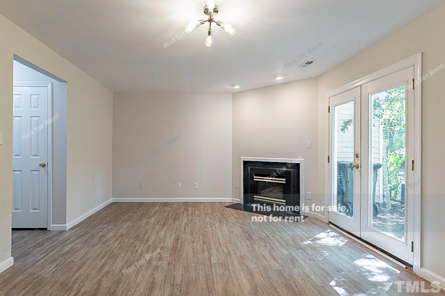565 Darby Glen Lane Durham, NC 27713 - Photo 3 of 18 an empty room with wooden floor fireplace and windows