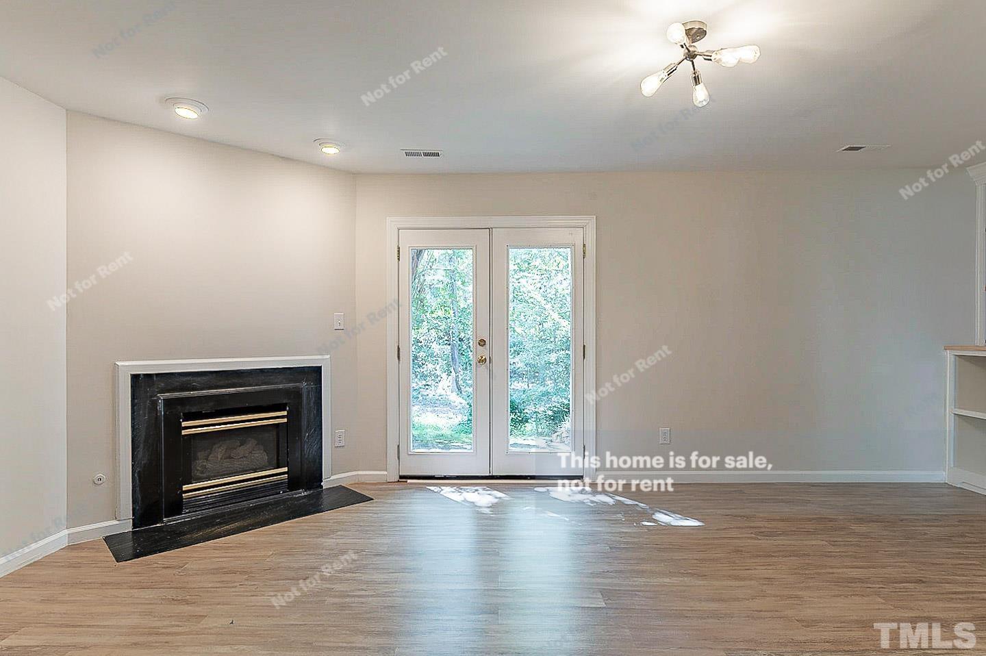565 Darby Glen Lane Durham, NC 27713 - Photo 4 of 18 an empty room with wooden floor fireplace and windows