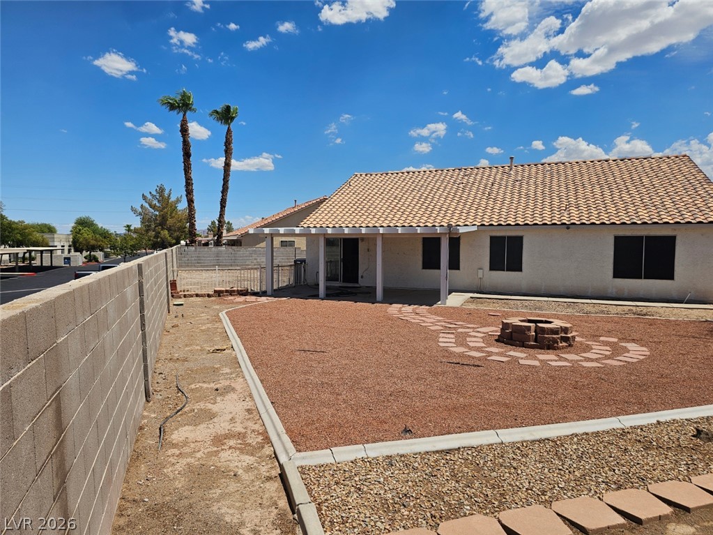 1418 Reebok Terrace Henderson, NV 89014 - Photo 38 of 38 A spacious backyard retreat features a covered patio, fire pit, and decorative landscaping.