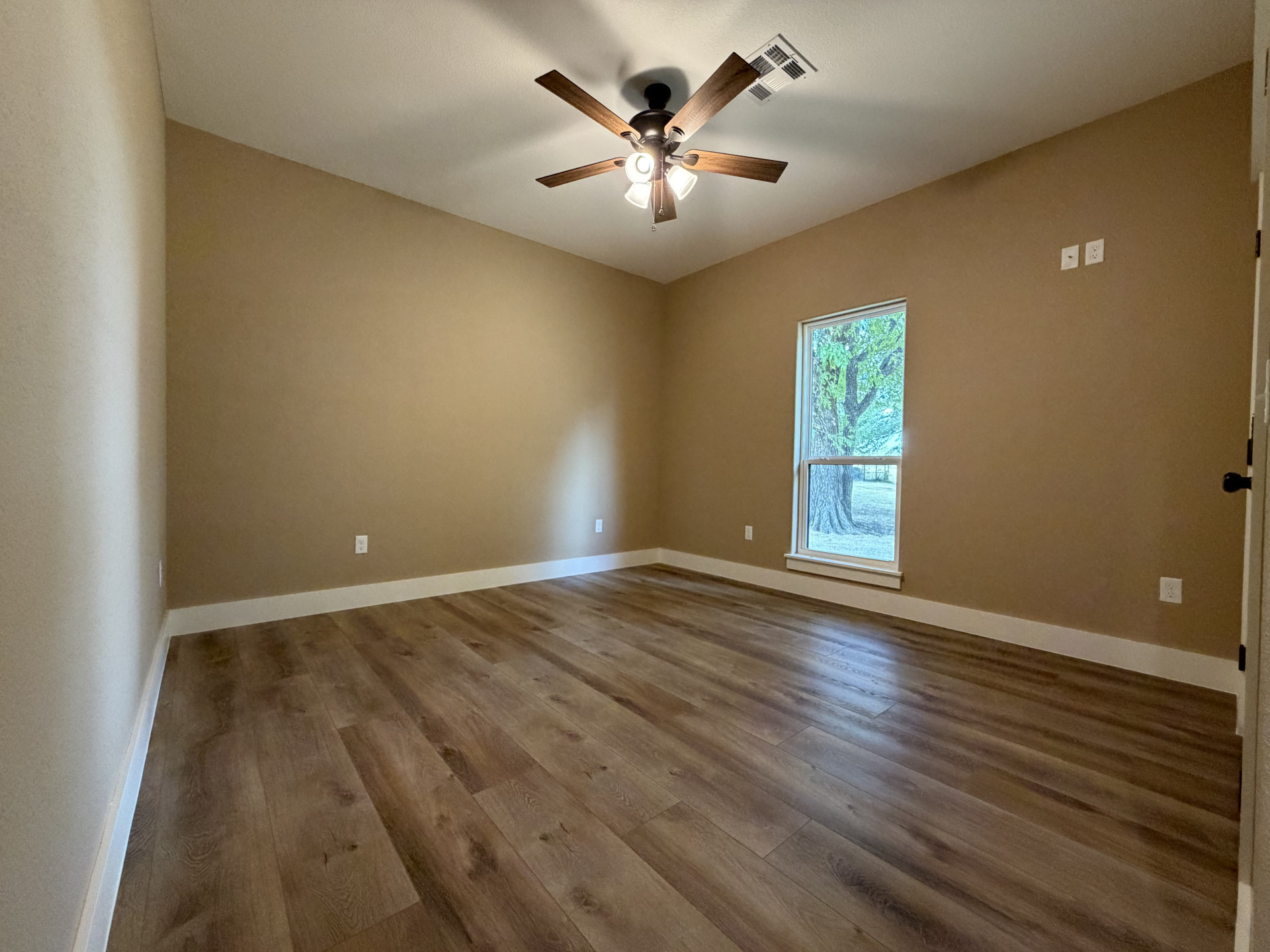 33 Wilderness Road North Calera, OK 74730 - Photo 22 of 39 Wood-finish flooring with crisp white trim, a large window, and a ceiling fan with light fixture