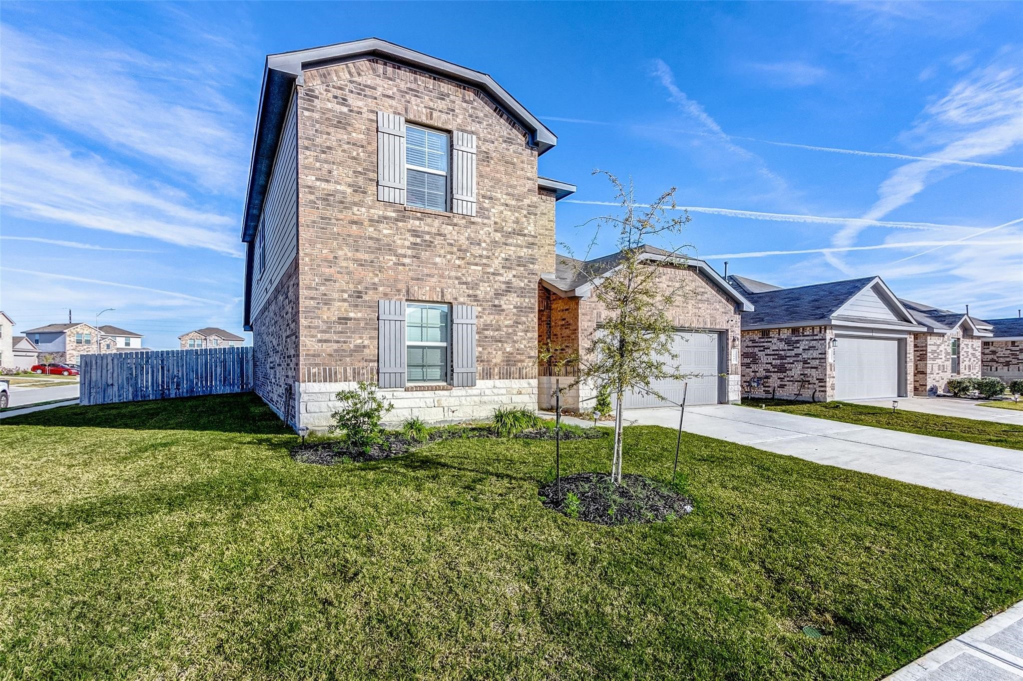 20846 Dryden Prairie Road Katy, TX 77449 - Photo 2 of 31 A side-angle view of a two-story brick home with stone accents shows a spacious grassy yard, young landscaping