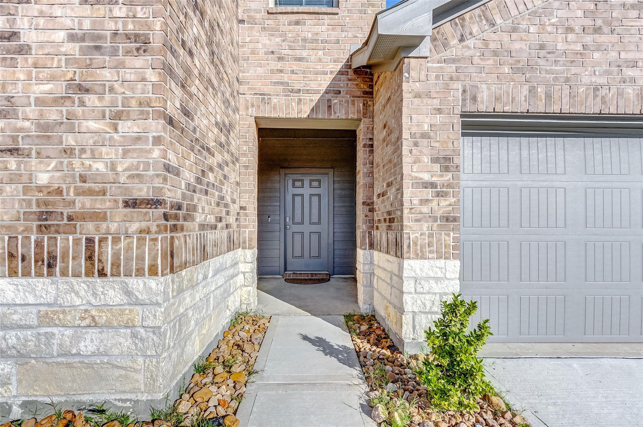 20846 Dryden Prairie Road Katy, TX 77449 - Photo 3 of 31 A covered front entryway features a gray door framed by brick and stone accents, a narrow concrete walkway, and minimal landscaping leading up to the home.