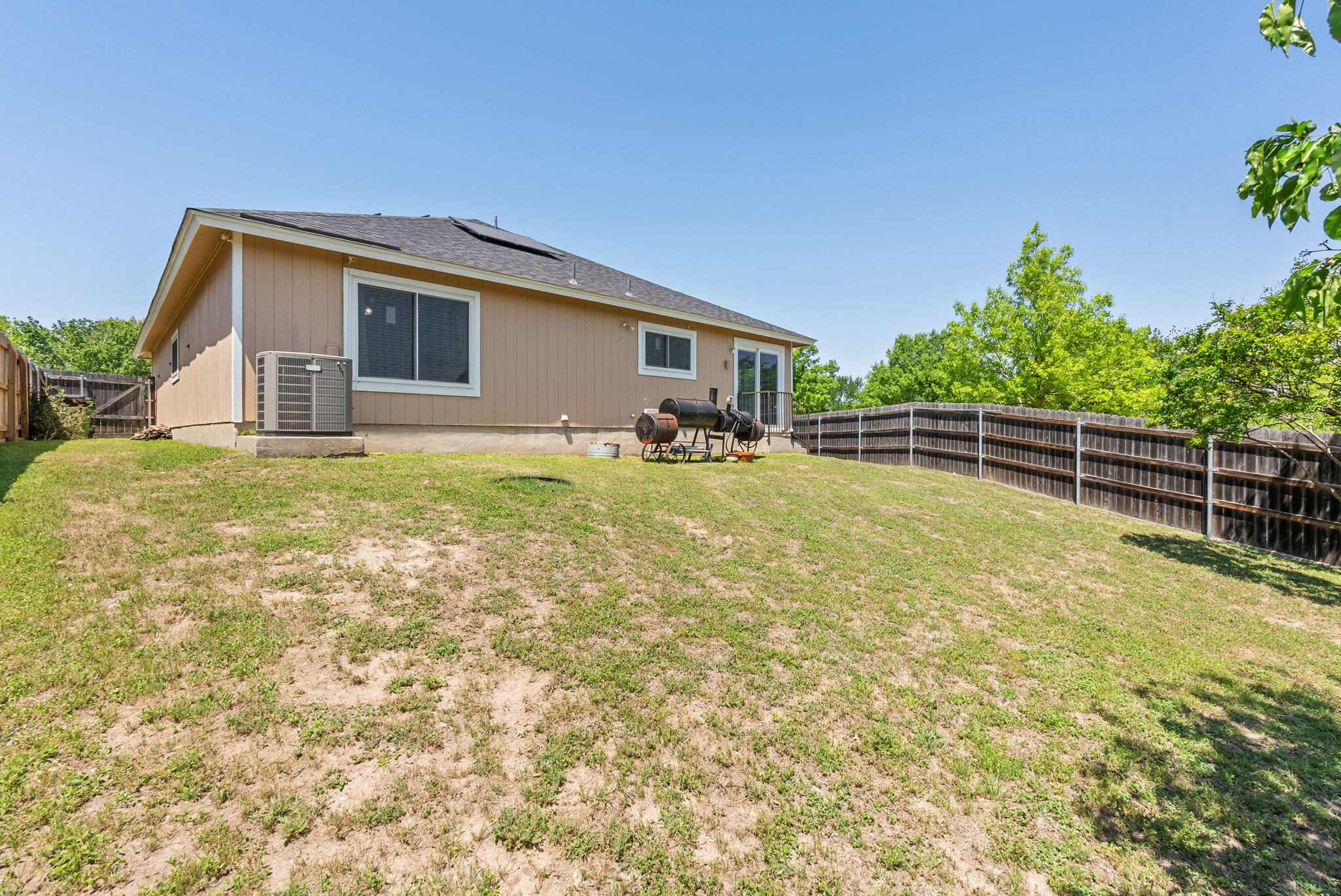 2617 Andres Way Round Rock, TX 78664 - Photo 20 of 21 Rear view of house with roof mounted solar panels, central air condition unit, a lawn, and a fenced backyard