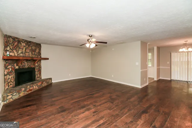 a view of an empty room with wooden floor fireplace and a window