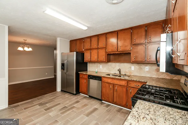 a kitchen with stainless steel appliances granite countertop a refrigerator and a sink