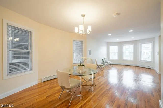 a dining room with wooden floor a chandelier a glass table and chairs