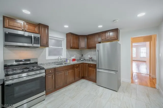 a kitchen with granite countertop a refrigerator stove top oven and sink