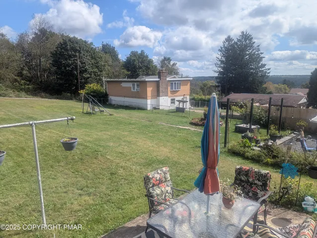 a view of a backyard with table and chairs under an umbrella