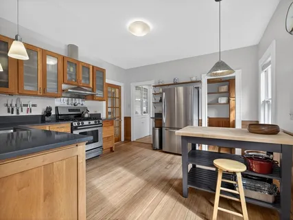 a kitchen with kitchen island granite countertop a stove a sink dishwasher a refrigerator cabinets and wooden floor