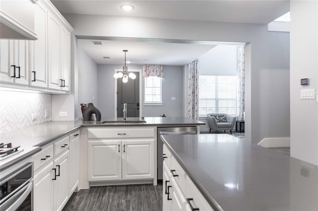 631 Cobblestone Lane Irving, TX 75039 - Photo 7 of 32 a kitchen with a sink dishwasher and white cabinets with wooden floor