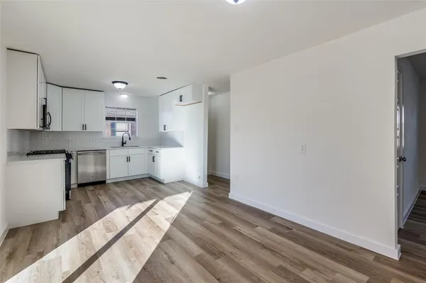 a kitchen with a white cabinets and wooden floor