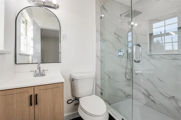 a bathroom with a toilet sink vanity granite and shower