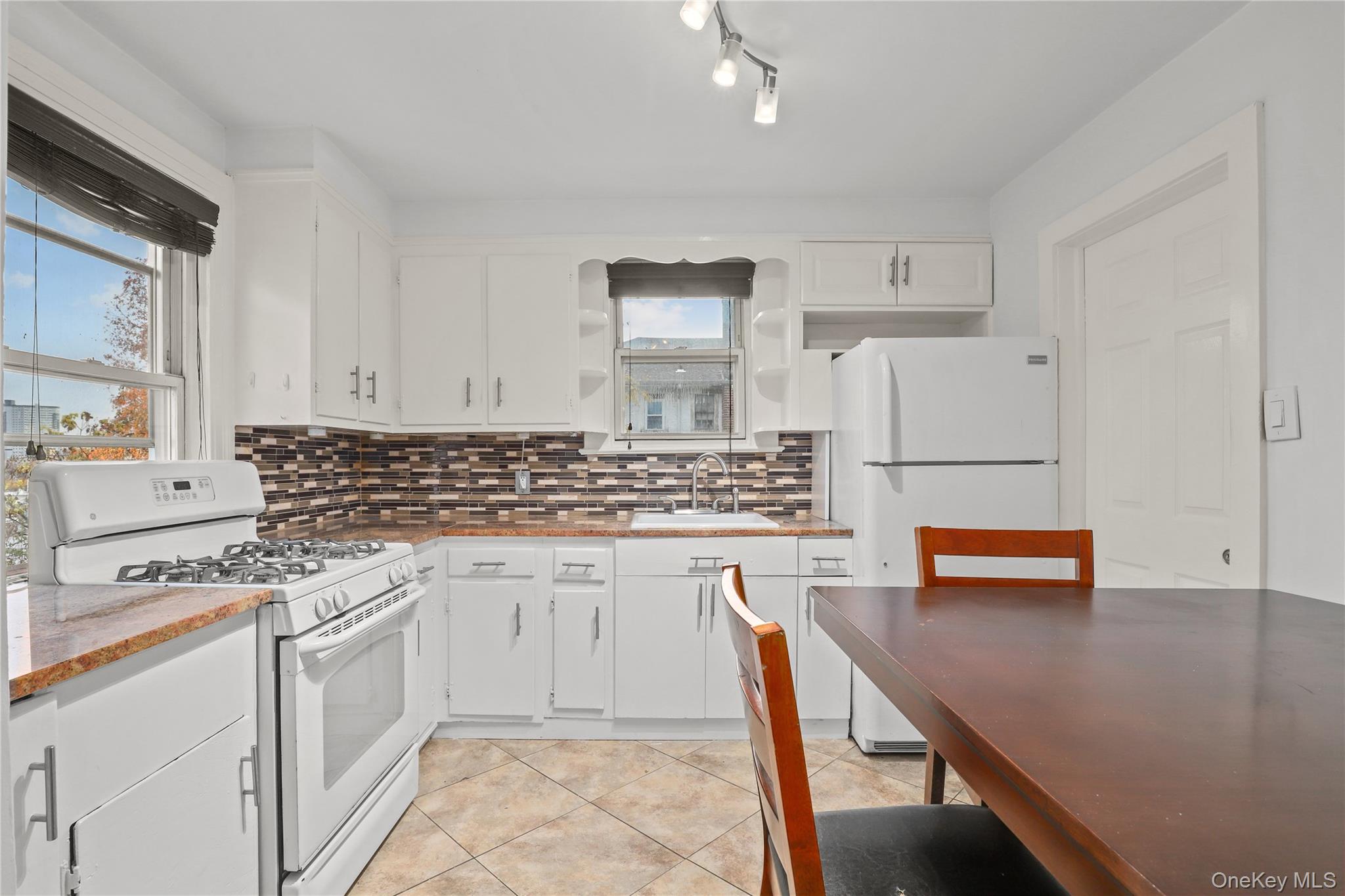 69 Clinton Avenue New Rochelle, NY 10801 - Photo 13 of 29 a kitchen with a refrigerator and white cabinets