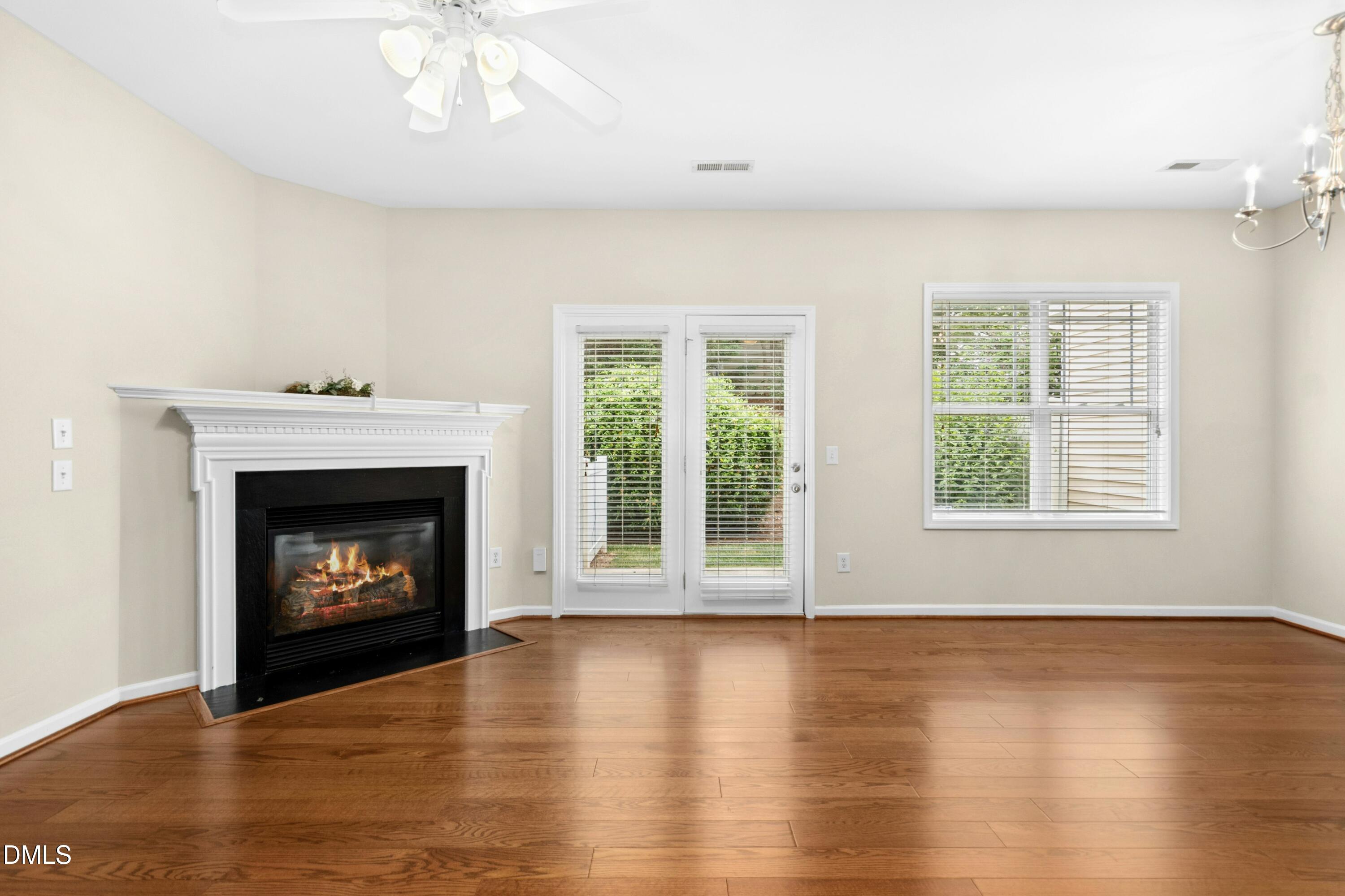 5541 Nur Lane Raleigh, NC 27606 - Photo 11 of 33 an empty room with wooden floor fireplace and windows