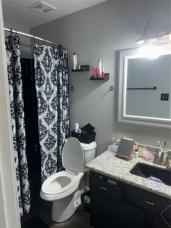 a bathroom with a granite countertop toilet sink and mirror