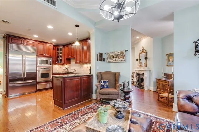 a living room with stainless steel appliances furniture a rug and a kitchen view