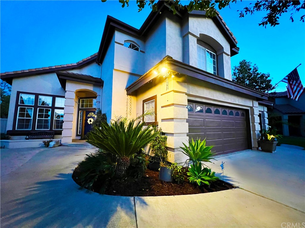 a view of a house with small yard plants and a lawn chair under an umbrella
