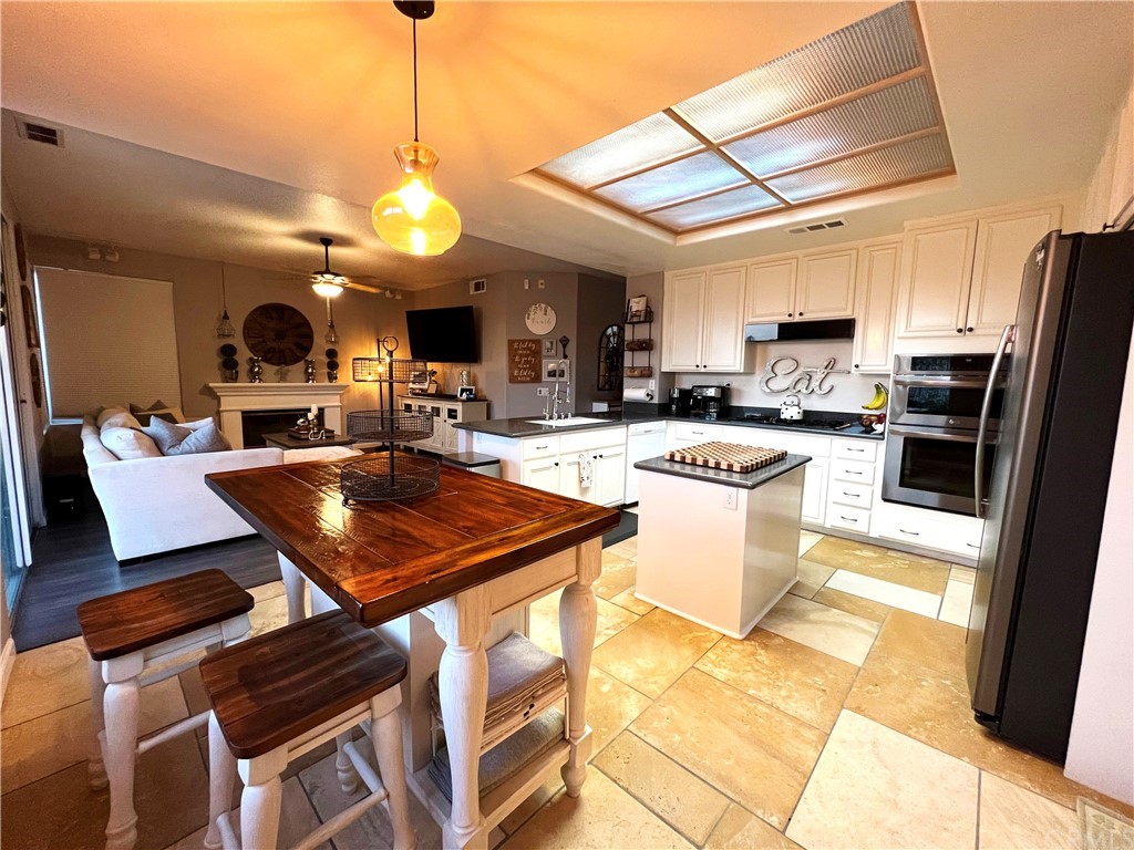 43 Corte Rivera Lake Elsinore, CA 92532 - Photo 9 of 32 a kitchen with stainless steel appliances granite countertop a stove a sink dishwasher a refrigerator a microwave oven with a dining table and chairs