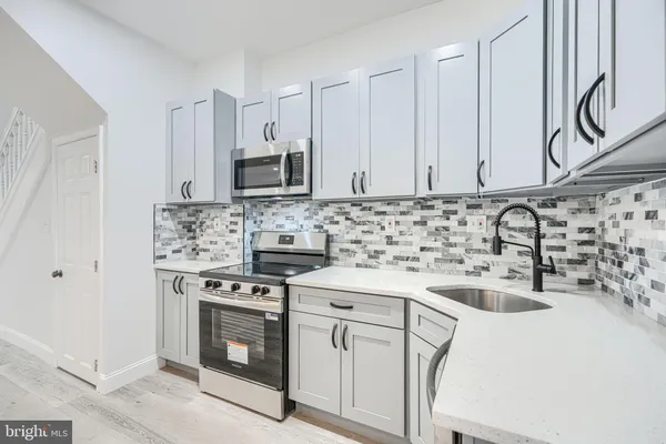 a kitchen with cabinets appliances a sink and a counter top space