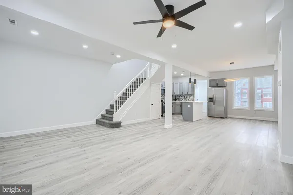 a view of an empty room with wooden floor stairs and a chandelier