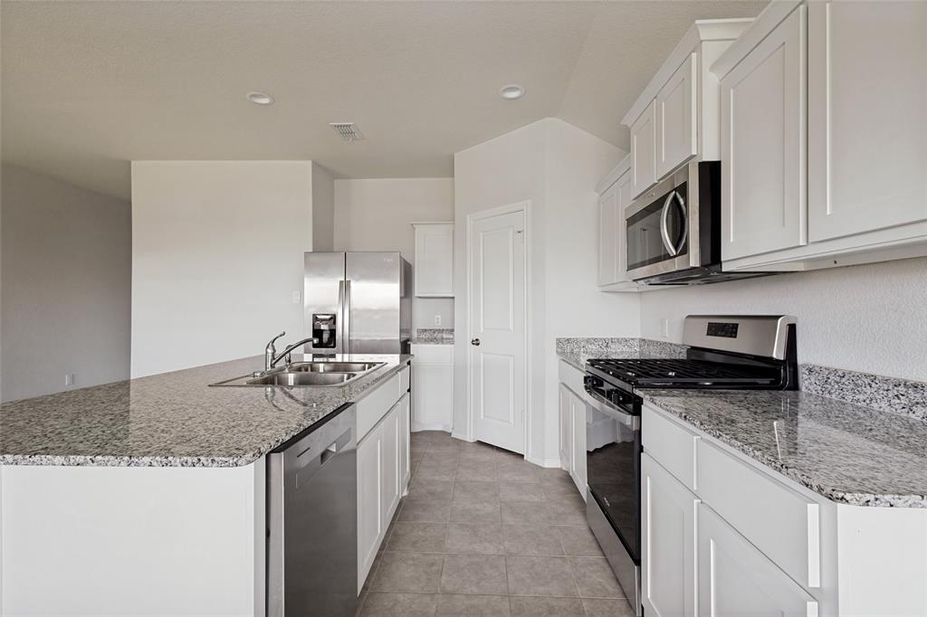 621 Spaulding Street Justin, TX 76247 - Photo 7 of 22 a kitchen with stainless steel appliances granite countertop a sink stove and cabinets