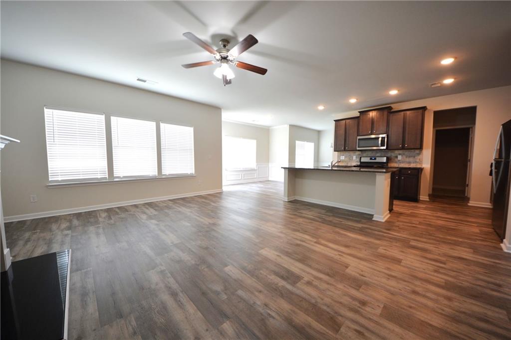 2377 Ticonic Road Lithonia, GA 30058 - Photo 17 of 40 a view of an empty room with wooden floor and a kitchen