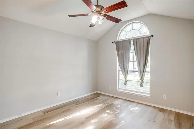 an empty room with a chandelier fan and windows