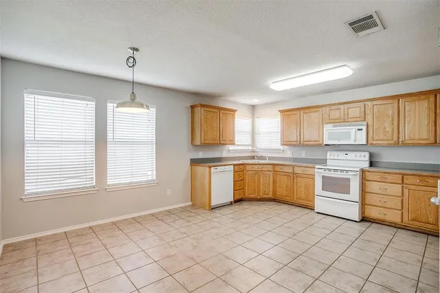 a large white kitchen with cabinets wooden floor and a sink