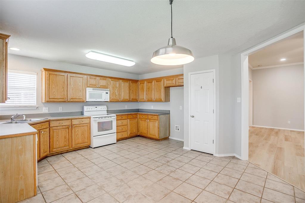 543 Thistle Meade Circle Burleson, TX 76028 - Photo 9 of 23 a large kitchen with kitchen island granite countertop a stove a sink a dishwasher a dining table and chair with wooden floor