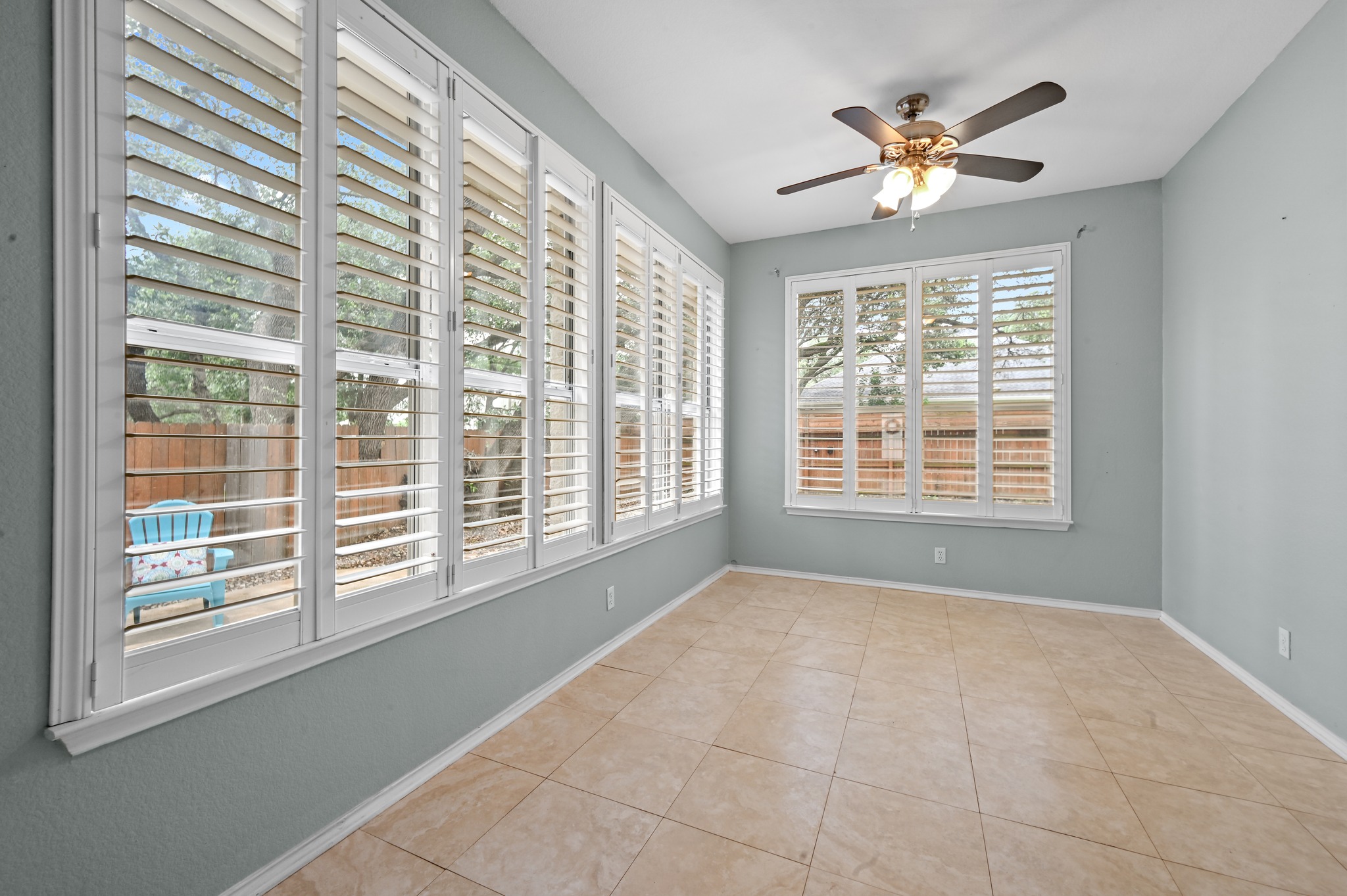 5313 Moon Shadow Drive Austin, TX 78735 - Photo 16 of 30 Room with extensive window array featuring plantation shutters, neutral tile flooring, a ceiling fan with integrated lighting, and light blue wall tones