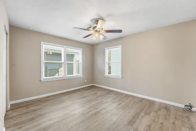 a view of an empty room with a window and wooden floor