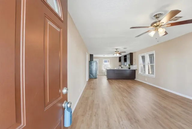 a view of an empty room with a window and wooden floor