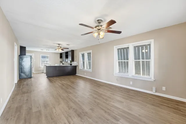 a view of an empty room with wooden floor and window
