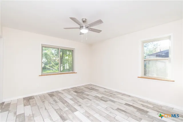 a view of empty room with wooden floor and fan