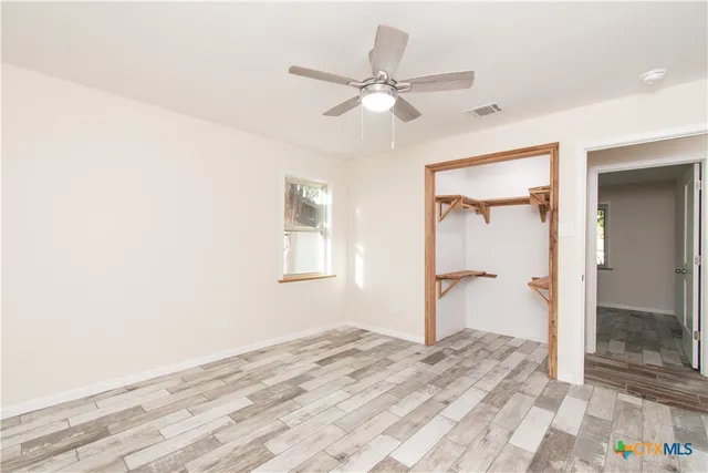 a view of a bedroom with wooden floor and a ceiling fan