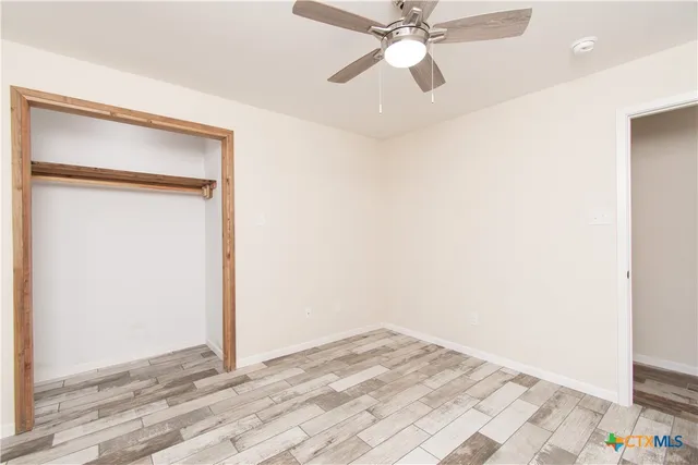 a view of a room with wooden floor closet and a ceiling fan