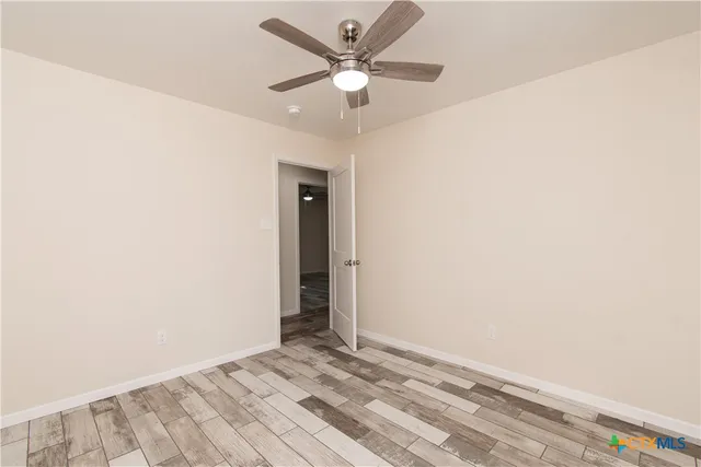 an empty room with a ceiling fan and carpet