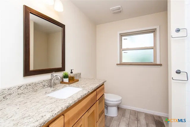 a bathroom with a granite countertop sink toilet and mirror