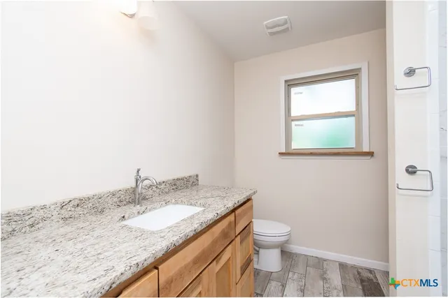 a bathroom with a granite countertop sink toilet and a mirror
