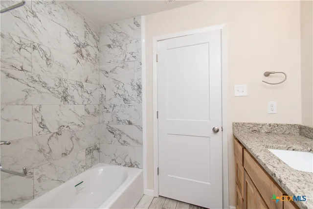 a bathroom with a granite countertop sink and a bathtub