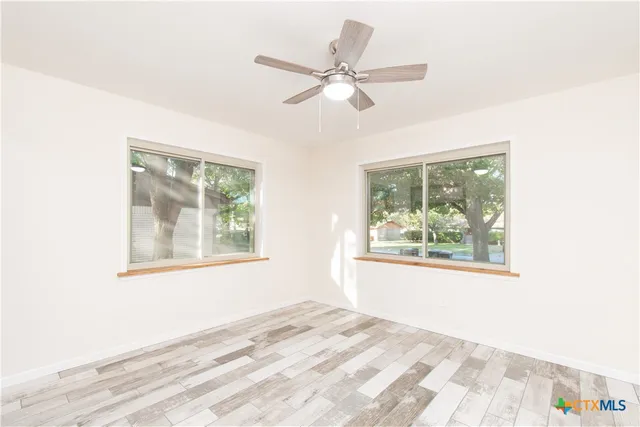 a view of an empty room with wooden floor and a window