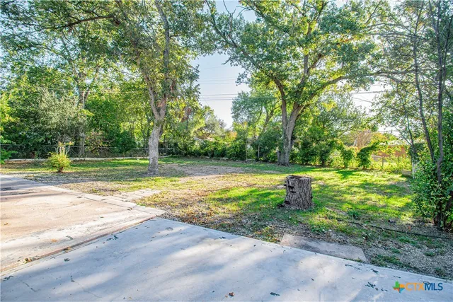 a view of a fountain in front of a house with large trees