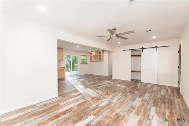 a view of a livingroom with a chandelier fan and wooden floor