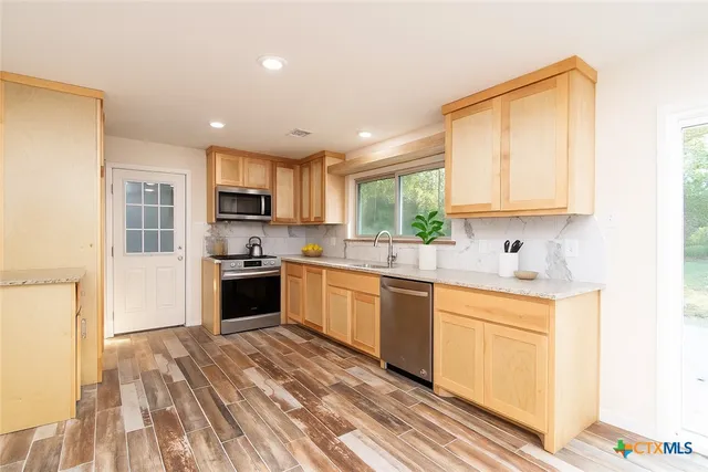 a kitchen with granite countertop a stove top oven sink and cabinets