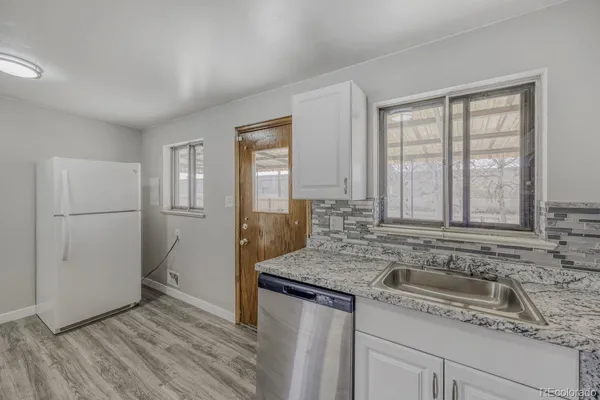 a kitchen with granite countertop a sink stove and refrigerator